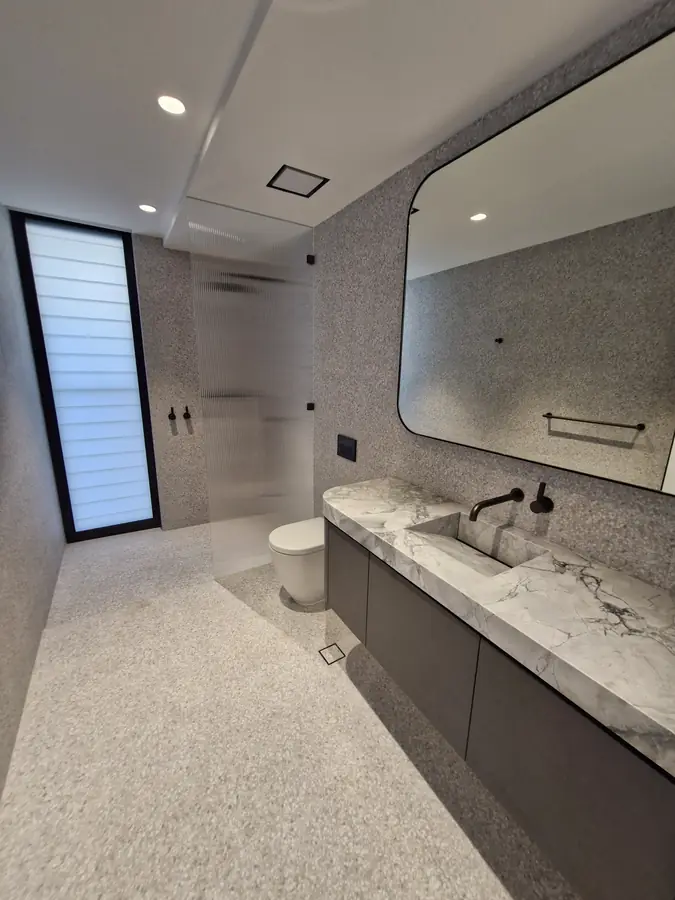 Bathroom with a dark marble vanity top and black-framed mirror
